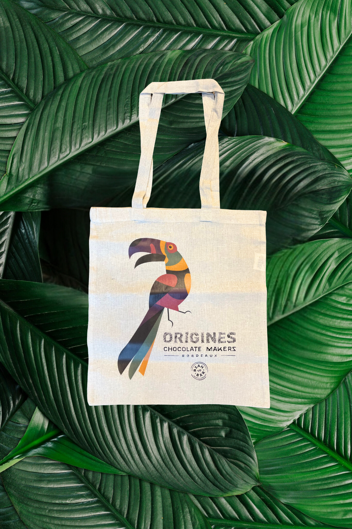Ajoutez une touche exotique à votre quotidien avec notre tote bag en coton biologique, illustré d’un magnifique toucan aux couleurs vibrantes. Symbole de la nature tropicale et de notre engagement pour un chocolat responsable, ce sac réutilisable vous accompagnera partout avec style.