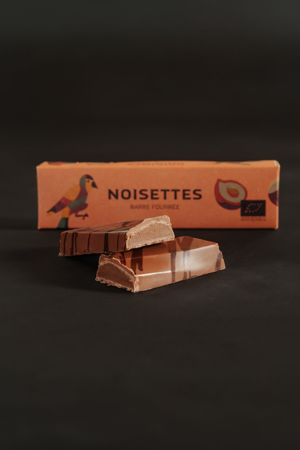 Barre chocolatée fourrée au noisettes avec un emballage marqué 'Noisettes', sur fond noir.