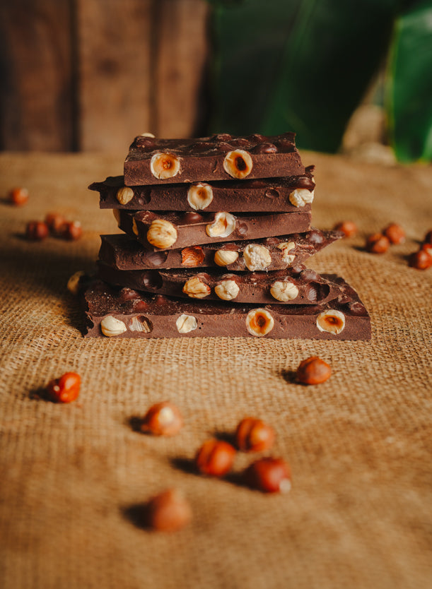 Morceaux de chocolat noir aux noisettes empilés sur une toile de jute, en arrière-plan naturel.